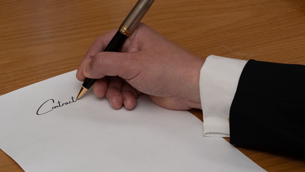 Mão assinando um contrato com caneta-tinteiro