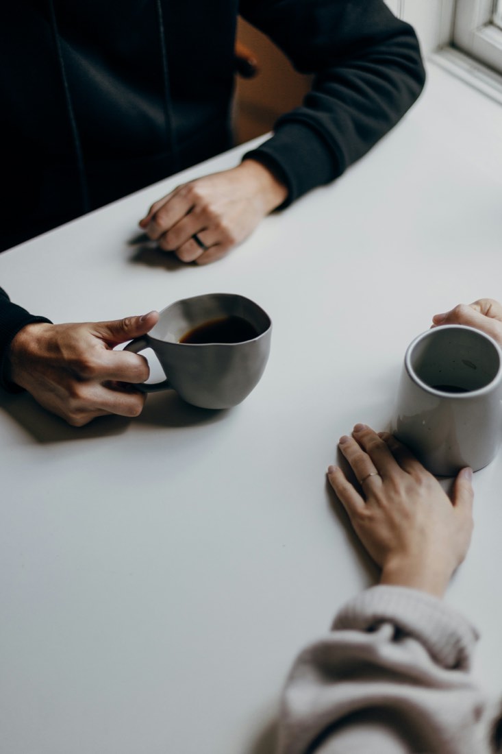 Duas pessoas conversando à mesa com café